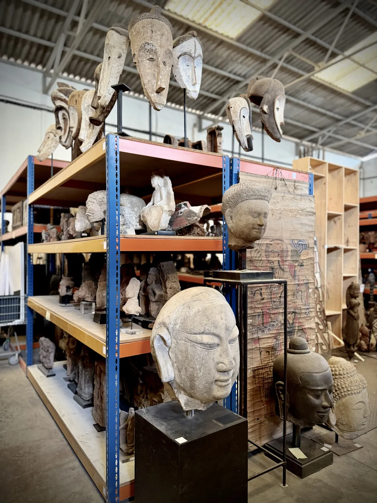Mixed storage shelves with African masks and stone Buddha heads