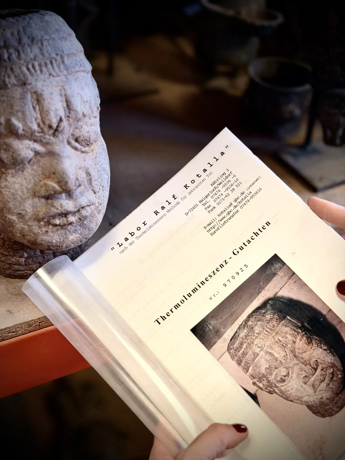A thermoluminescence dating report beside a stone head